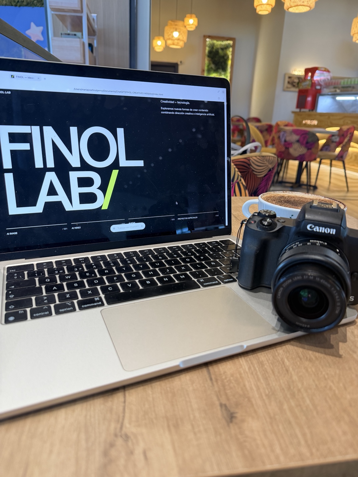 MacBook con FINOL LAB en pantalla junto a una cámara Canon